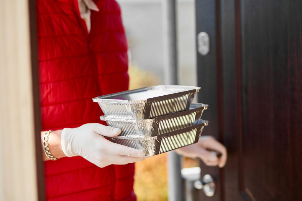 Courier handing over boxed food delivery at a door